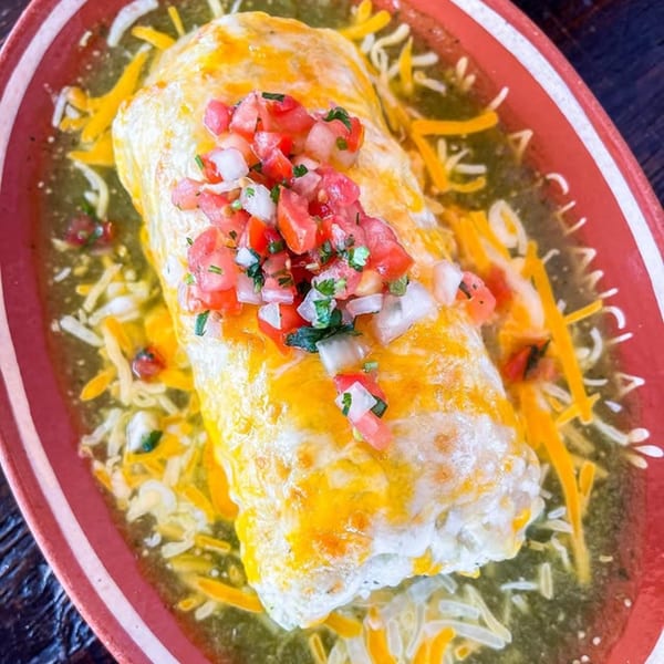 La Chancla Mexican Grill's wet burrito, smothered in green sauce, melted cheese, and fresh pico de gallo.