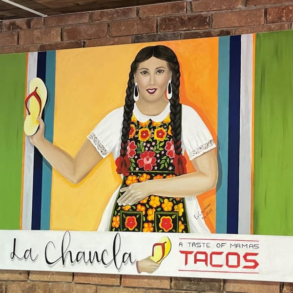 Colorful mural of a woman in traditional Mexican dress holding a yellow flip-flop, with "La Chancla Tacos" text.