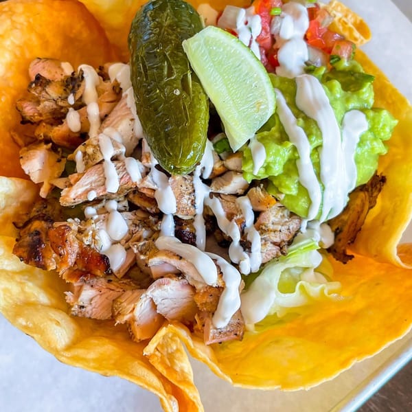 La Chancla Mexican Grill's chicken taco salad in a crispy tortilla bowl with guacamole and lime.