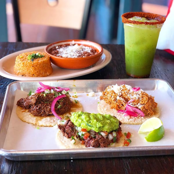 Three La Chancla Mexican Grill tacos, rice, beans, and a green drink with a chili-lime rim.